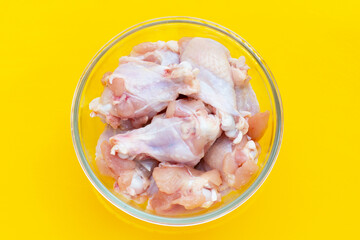 Fresh raw chicken wings (wingstick) in glass bowl on yellow background.