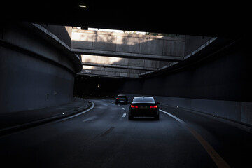 Black car is driving down the road in the tunnel. Traffic infrastructure, tunnel architecture,...