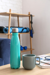 Bottle of water and cup on table in room