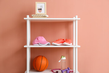 Shelf unit with sport equipment and photo frame near color wall