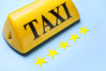 Yellow taxi roof sign and paper stars on blue background
