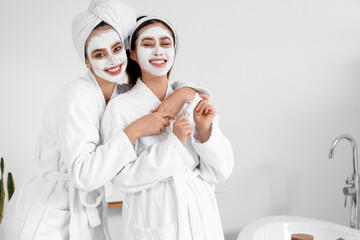 Beautiful young women with applied facial masks in bathroom