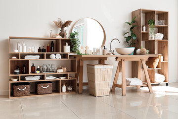 Stylish interior of bathroom with modern sink and shelf units with bath accessories near white wall