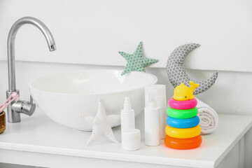 Different bath accessories for children and toys near modern sink on table