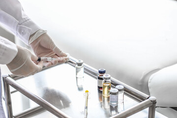 Female doctor with syringe near table in clinic, closeup