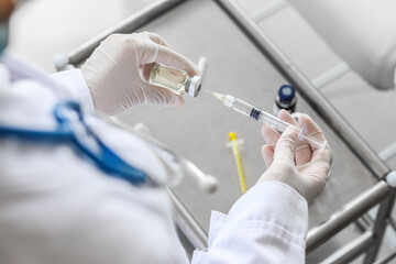 Female doctor with syringe and ampule in clinic, closeup