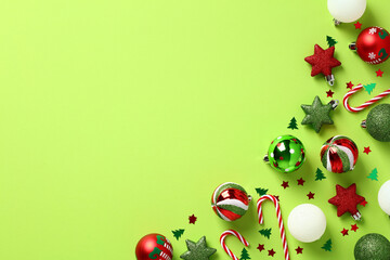 Red and green Christmas decorations, baubles, candy canes, confetti on light green background. Christmas holiday greeting card template.