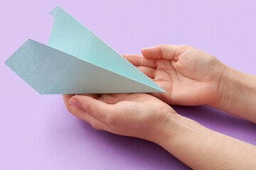 Woman with blue paper plane on lilac background