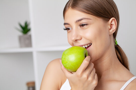 Beautiful Young Girl With White Teeth Holding Hands Of Fresh Green Apple.