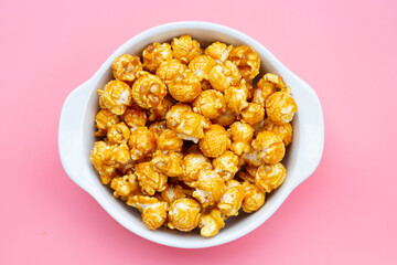Honey caramel popcorn on pink background.