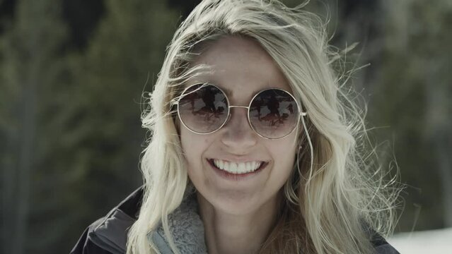 Close up of laughing girl with sunglasses looking at camera in winter / Tibble Fork, Utah, United States