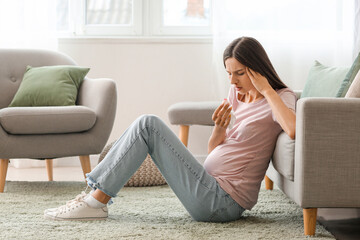 Young pregnant woman with nosebleed and tissue at home