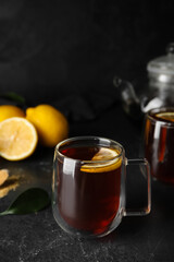 Glass cup of black tea with lemon on dark background, closeup