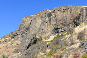 Basalt cliff face rises above a dry slope in Central Washington