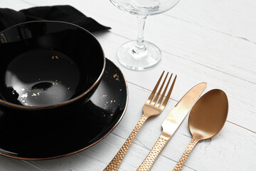 Stylish table setting with golden cutlery on light wooden background, closeup