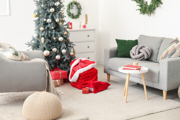Stylish interior of modern living room with beautiful Christmas tree, Santa bags and gifts