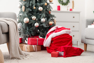 Santa bags with gifts near Christmas tree in room