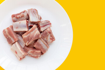 iRaw pork ribs in white plate on yellow background
