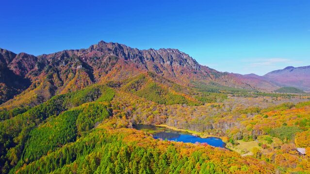 紅葉の美しい秋の戸隠連峰と鏡池の鏡面のドローン空撮