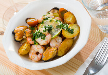 Tasty stewed potato served on plate with seafood - shrimps and mussels