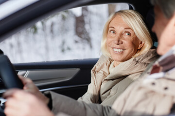 Portrait of smiling mature woman enjoying car ride with husband in winter