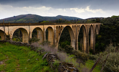 Fototapeta na wymiar Impressive view of old railway bridge Viaduct of Guadalupe, Spain, at cloudy spring day