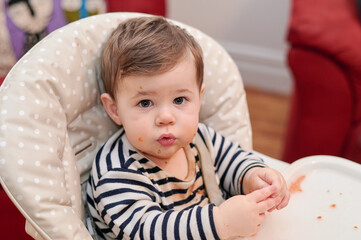 cute boy eating tomatoes in his high chari