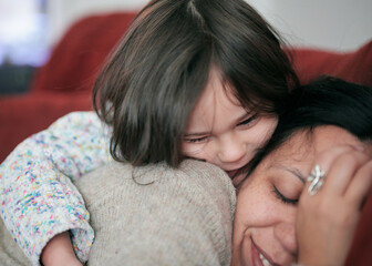 pretty young girl hugging  mom on the couch