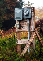 Electric meter with power mounted to wooden board, vertically braced to stand alone in a wooded lot in an area to be developed and built on. 