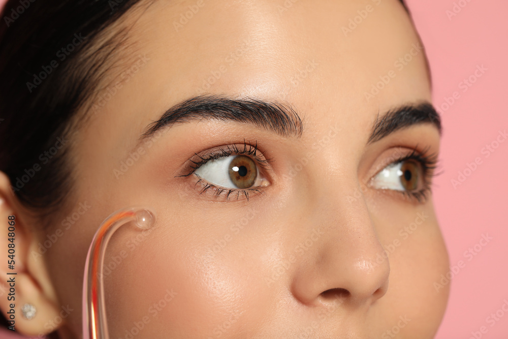 Poster Woman using high frequency darsonval device on pink background, closeup