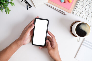 From above view of man hands holding mobile phone with white empty screen.