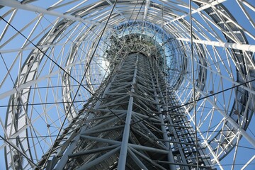 Structure of modern tower against blue sky, bottom view