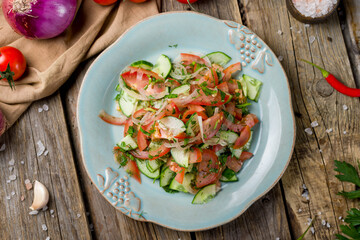 Vegetable salad with tomatoes and cucumbers and red onion on old wooden table top view