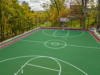 Aerial photo of a green and red outdoor basketball court at school playground.  Court includes...