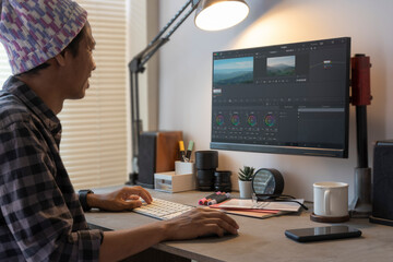 Male videographer editing video footage on professional computer at her workstation.