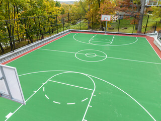Aerial photo of a green and red outdoor basketball court at school playground.  Court includes...