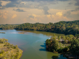 Naklejka premium Morgan Fall Overlook Park on sunny Fall day. Aerial river view with Fall and Autumn colored trees. Drone shot. Rolling storm clouds