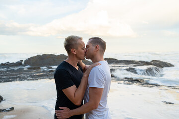 gay couple kissing with waves behind them