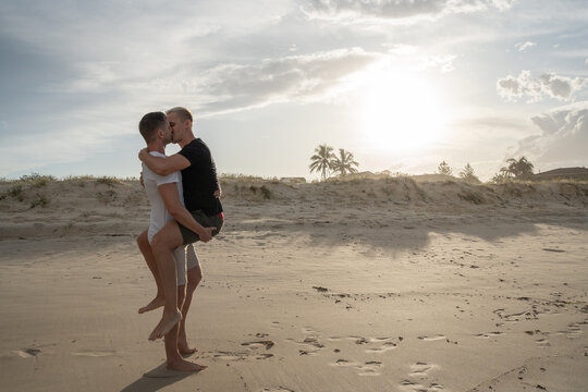 gay couple hugging and kissing on beach