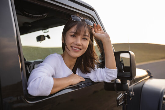 Happy young woman looking out of car window