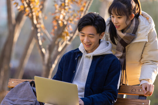 Happy college students using laptop on campus