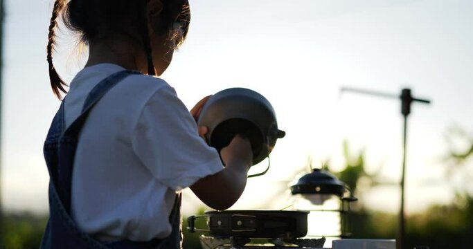 Backlit Handheld Close up shot, Cute little girl enjoy play to cooking in pot