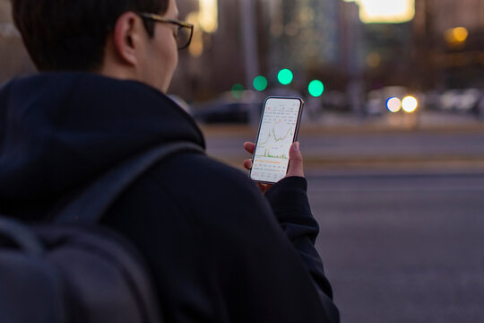 A man checking stock market data on smartphone - Powered by Adobe