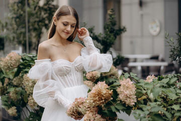 Attractive woman wearing wedding dress admiring flowers.