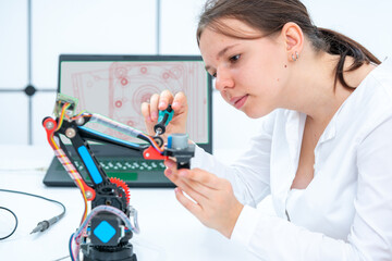 schoolgirl student adjusts industrial robot arm model