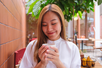 Portrait image of a beautiful young asian woman holding and drinking hot coffee