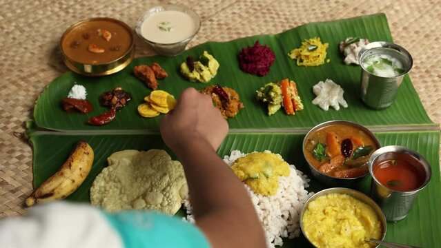Traditional Onam sadhya rice Sambar, Rasam, parippu dal curry ghee Pappadom Payasam on banana leaf Onam Vishu Pongal Diwali festival vegetarian food Kerala Tamil Nadu South India. 4k video footage