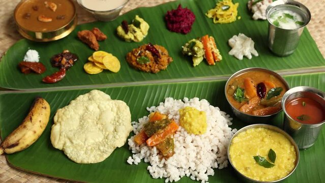 Traditional Onam sadhya rice Sambar, Rasam, parippu dal curry ghee Pappadom Payasam on banana leaf Onam Vishu Pongal Diwali festival vegetarian food Kerala Tamil Nadu South India. 4k video footage