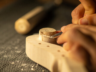 luthier artisan maker sculpting and carving violin scroll and neck with chisel