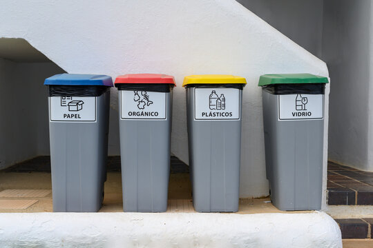 Four recycling garbage cans, reading in spanish: paper, organic, plastic and glass.